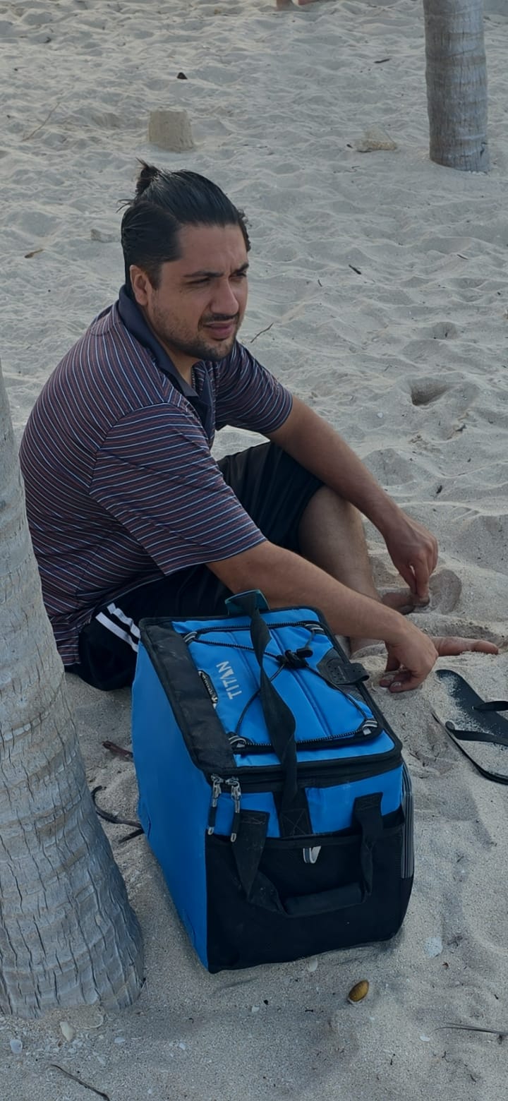 Carlos Eduardo Ibarra López sentado en la arena de la playa